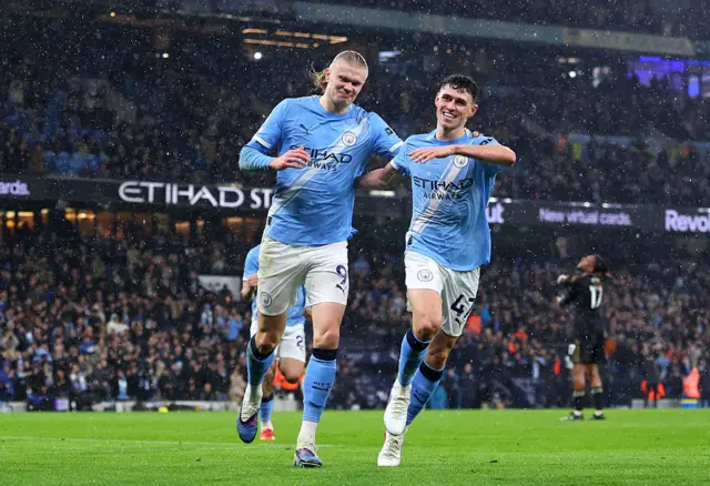 Erling Haaland celebrates scoring his team's third goal with Phil Foden