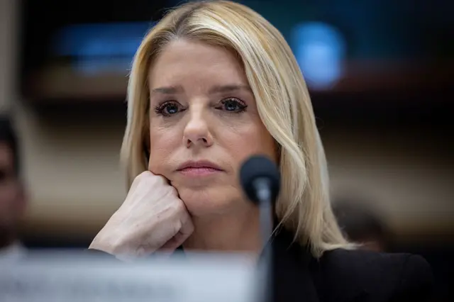 A blonde woman rests her head on a fist