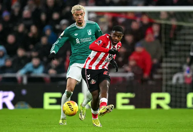 Noah Sadiki passes the ball whilst under pressure from Hugo Ekitike
