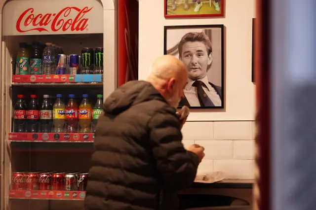 A fan sits in a chip shop in front of a picture of Brian Clough, former Nottingham Forest manager