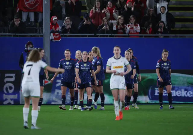 Arsenal players walk back to kick off after celebrating a goal