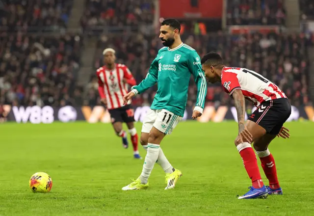 Mohamed Salah passes the ball whilst under pressure from Reinildo Mandava