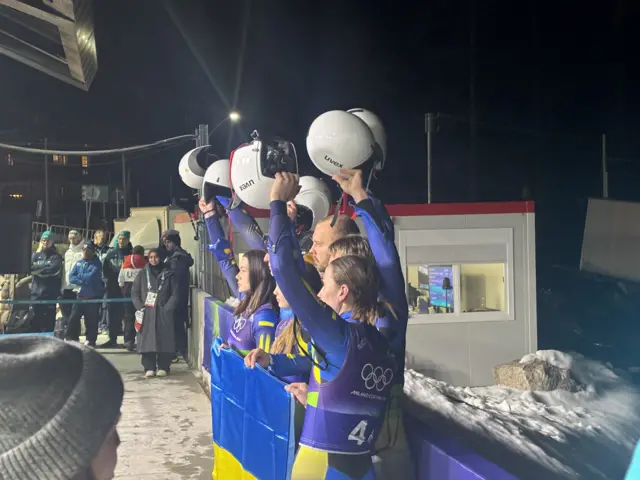 Team Ukraine hold helmets aloft at luge
