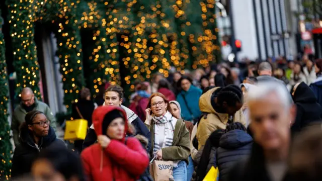 A busy shopping strip in London with Christmas lights in the background.