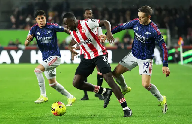 Michael Kayode of Brentford is challenged by Leandro Trossard of Arsenal