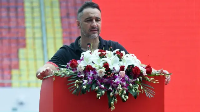 Vitor Pereira stands at a podium with flowers during his time at Shanghai