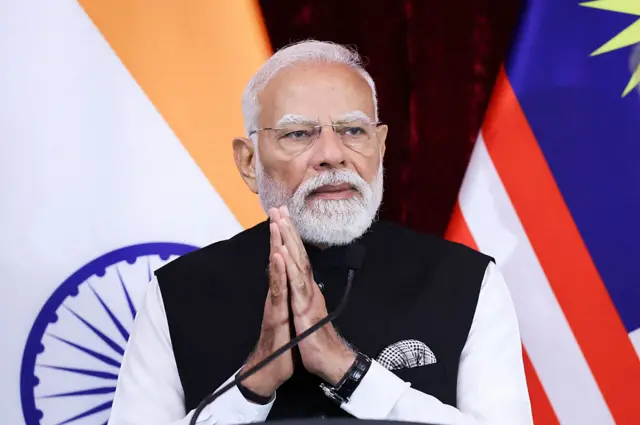 A close up shot of Indian Prime Minister Narendra Modi with his hands clasped together