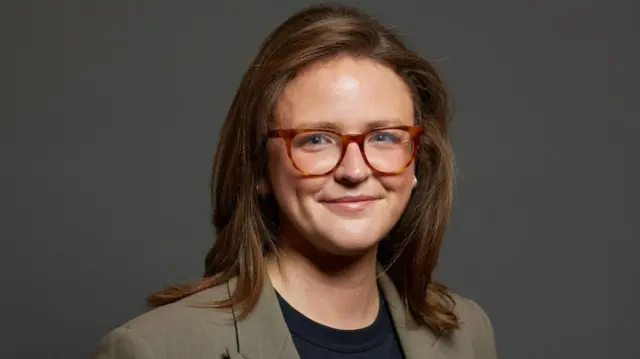 A woman with brown hair and glasses.