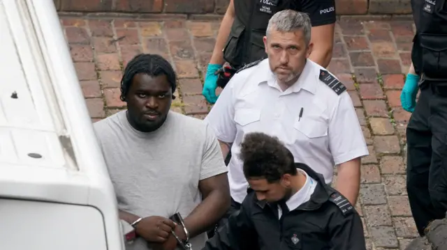 A man is led by police.
