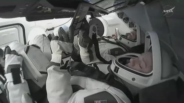 One of the astronauts is seen reading from a tablet
