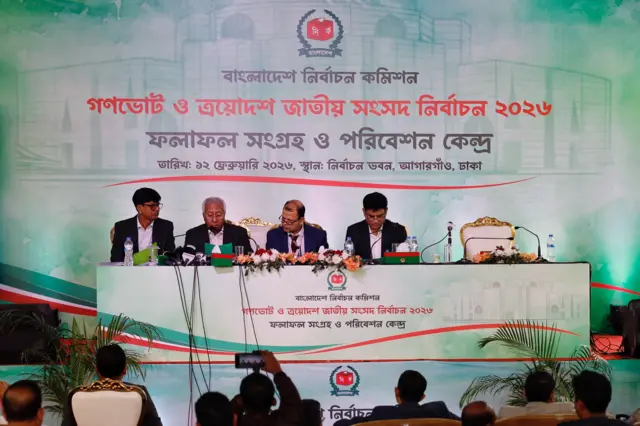 A row of speakers behind a podium announcing election results