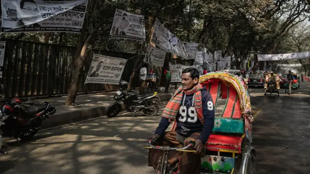 Man driving motorbike past election campaign posters in Bangladesh