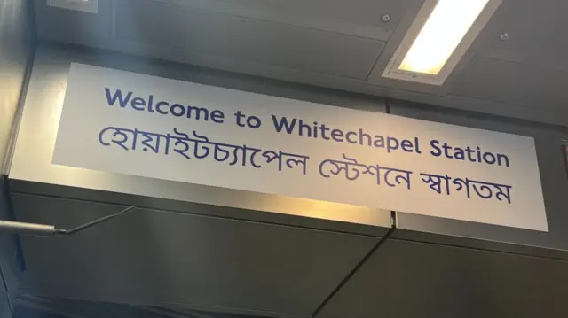 A bilingual sign in English and Bengali saying “Welcome to Whitechapel Station”
