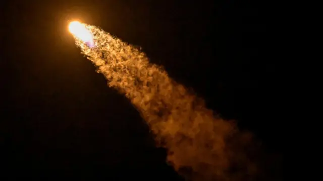 A bright streak of orange can be seen against a dark sky as the rocket heads to space