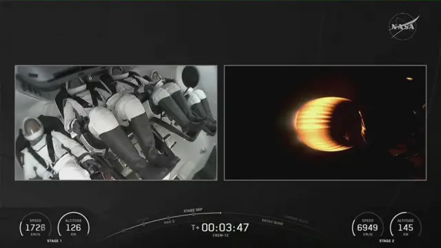 The astronauts are seen in their seets on one side while a rocket burns on a second screen