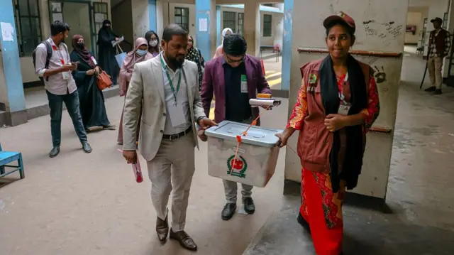 Two people holding a box full of ballots