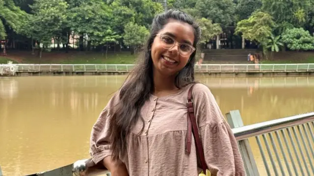 Young woman standing on a pedestrian bridge over a river