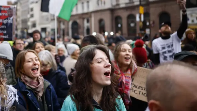 Supporters of Palestine Action hold banners outside Royal Courts of Justice as they celebrate winning a legal challenge against the decision to proscribe the group under anti-terrorism laws, in London
