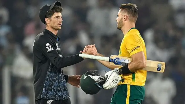 South Africa's captain Aiden Markram (R) is congratulated by his New Zealand counterpart Mitchell Santner