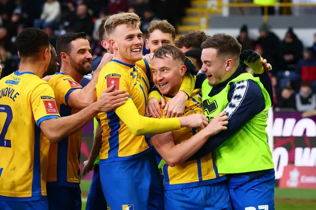 Louis Reed is mobbed after giving Mansfield a late lead