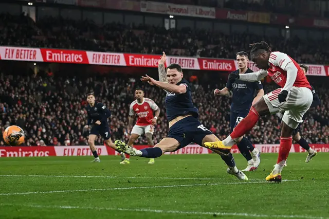 Wigan Athletic's Scottish goalkeeper #15 Jason Kerr (C) tries to defend against a shot by Arsenal's English midfielder #10 Eberechi Eze