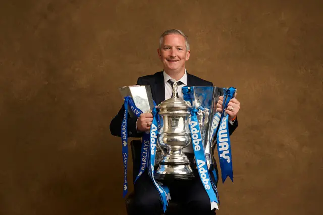 Paul Green poses for a photo with the three trophies Chelsea won last season