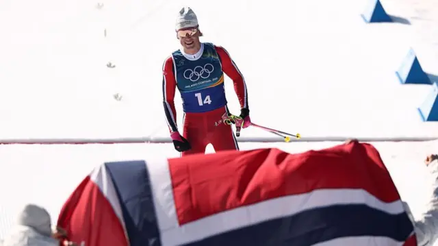 Klaebo smiling with a Norway flag