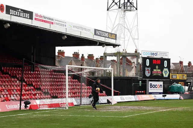 Referee, Samuel Barrott (R) and a Grimsby Town groundsman inspect the pitch