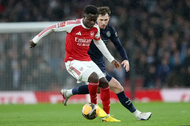 Bukayo Saka of Arsenal battles for possession with Jensen Weir