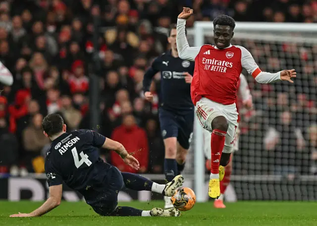 Bukayo Saka (R) fends off a tackly by Wigan Athletic's English defender #04 Will Aimson