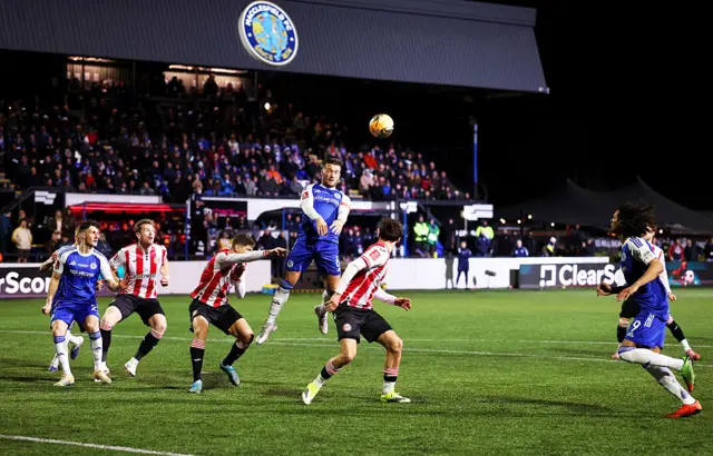 General view inside the stadium as Paul Dawson of Macclesfield wins a header during the Emirates FA Cup Fourth Round match between Macclesfield and Brentford at Moss Rose Ground on February 16, 2026 in Macclesfield, England.