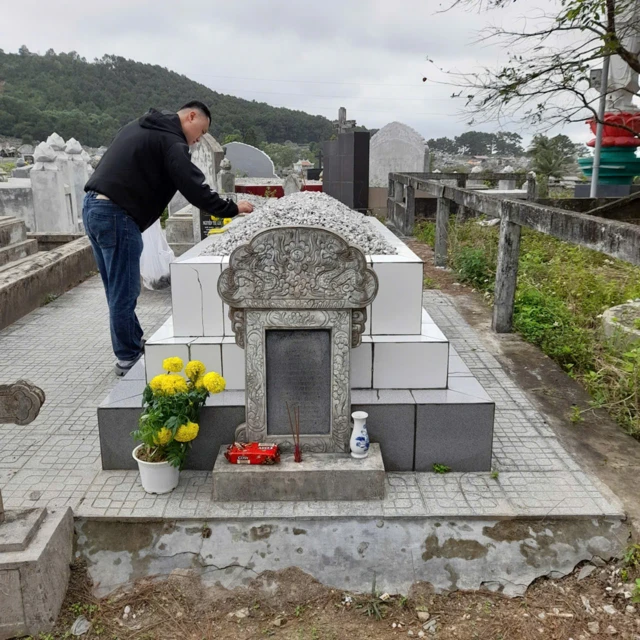 Man offering food and incense at a tomb in Vietnam