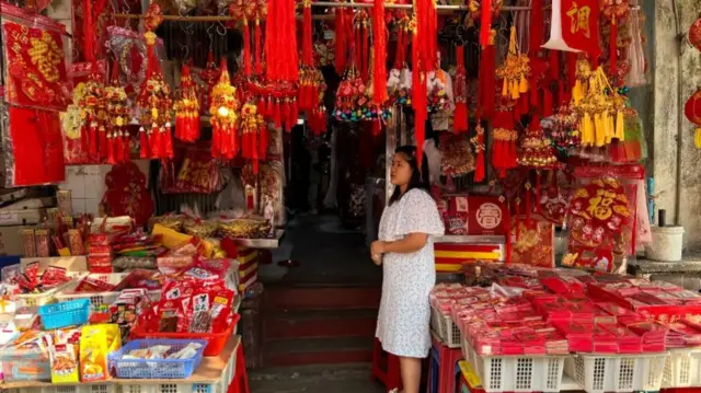 Woman standing in a store filled with Lunar New Year charms