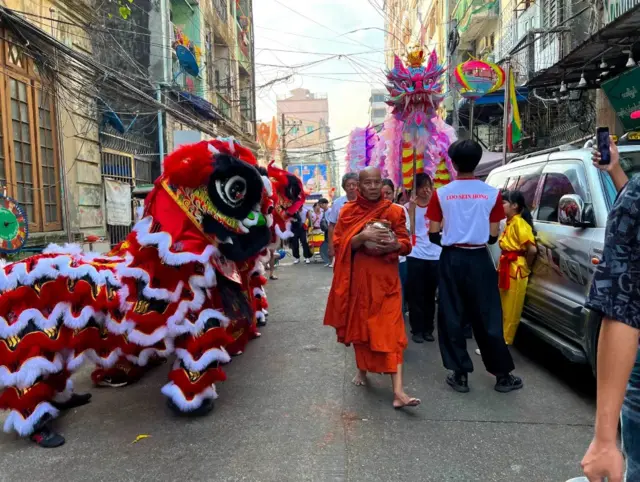 A monk walks past a row of lion dancers