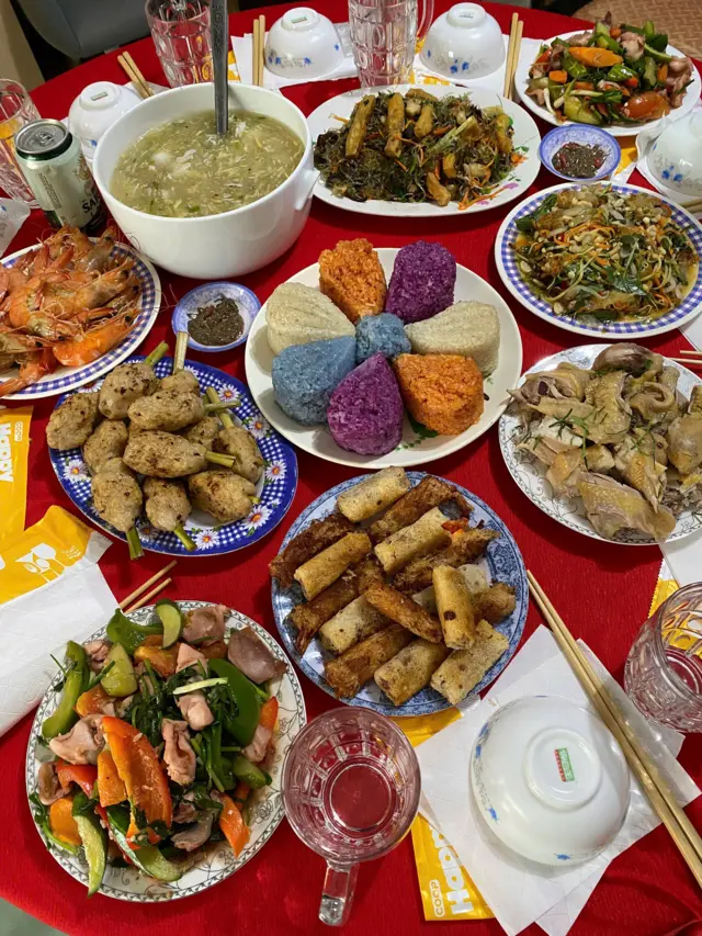 A spread of Vietnamese food on a table covered in red tablecloth