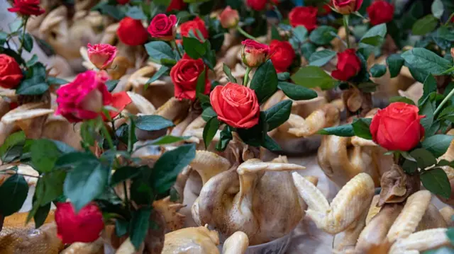 Rows of boiled whole chickens decorated with red roses