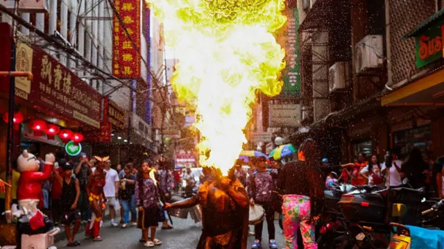 Street performer breathes fire at a Chinatown street