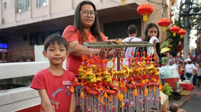 Mother and son wearing red selling horse charms for Lunar New Year