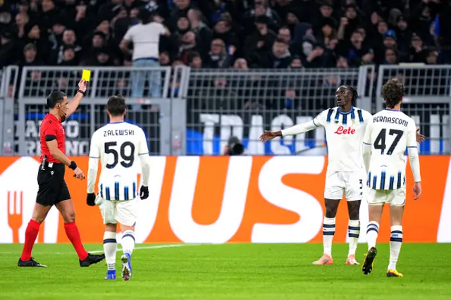 Referee Serdar Gozubuyuk, shows a yellow card to Odilon Kossounou of Atalanta