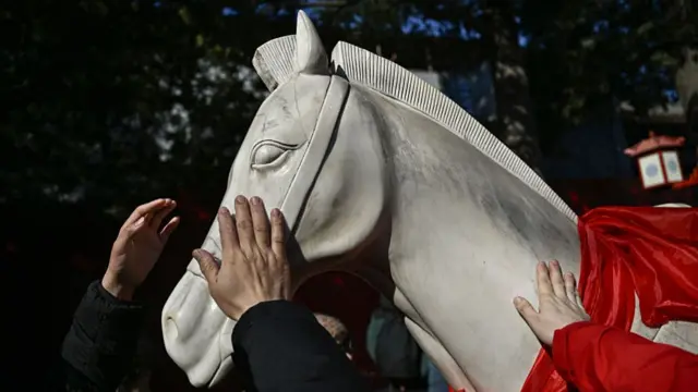 A white horse statue touched by human hands