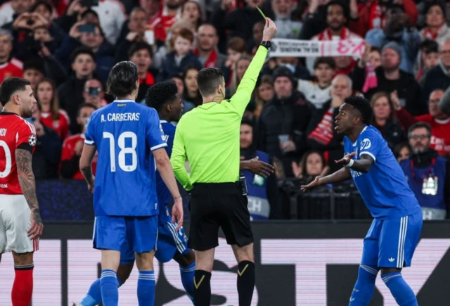 The referee Francois Letexier (L) shows the yellow card to Real Madrid's Vinicius Junior