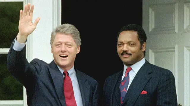 Bill Clinton waves as Jesse Jackson stands by his side
