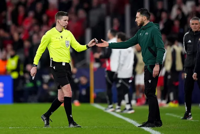 Referee Francois Letexier hands an object thrown from the stands to the fourth official