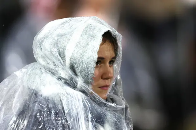 Fan looks on whilst wearing a rain poncho
