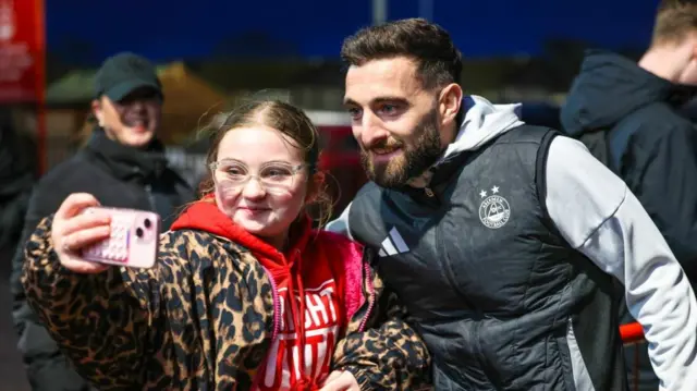 Graeme Shinnie poses for a photo with a young Aberdeen supporter