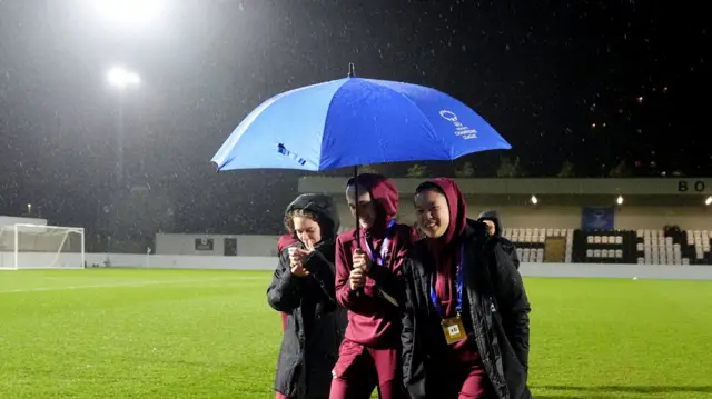 Leuven players check the pitch under an umbrella
