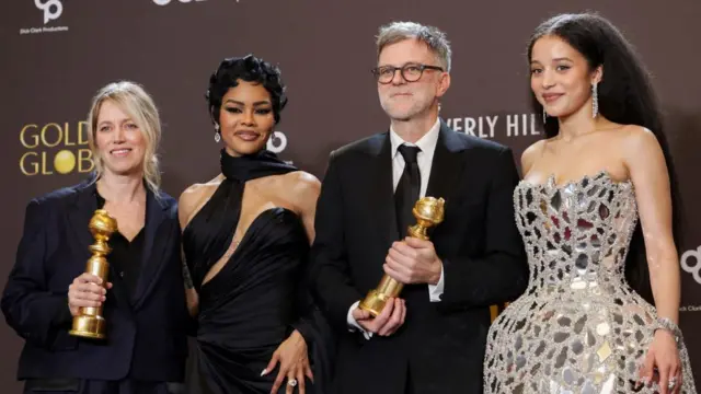 Sara Murphy, Teyana Taylor, Paul Thomas Anderson and Chase Infiniti standing in a line. Two hold gold awards, they smile