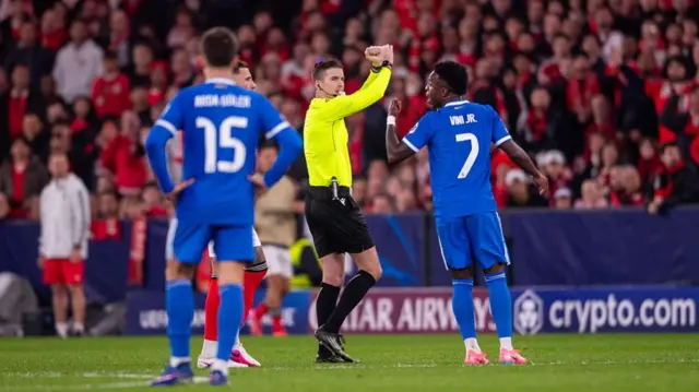 The referee signals an X with his arms during the game between Real Madrid and Benfica