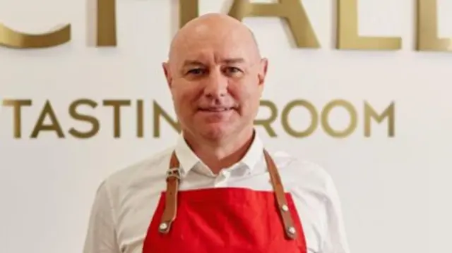Daniel Graham, managing director of Birchall, wearing a red apron and standing in front of a sign that reads: Birchall master tasting room