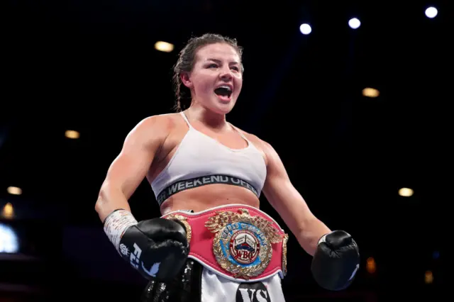 Sandy Ryan wears the WBO welterweight title around her waist and has black boxing gloves on her hands